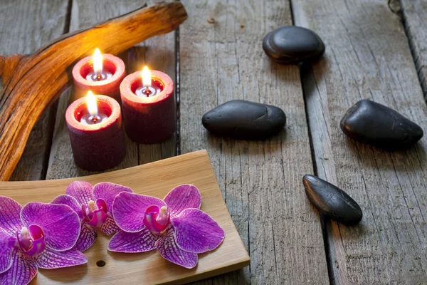 Piedras de spa orquídeas y velas sobre tablas de madera —  Fotos de Stock