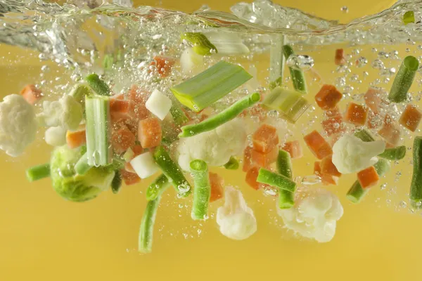 Vegetais salpicam em conceito de cozinha sopa de água — Fotografia de Stock