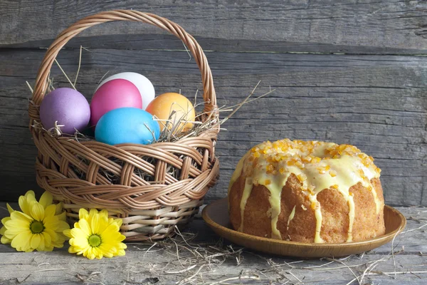 Uova di Pasqua nel cestino e torta sul tavolo di legno vintage — Foto Stock