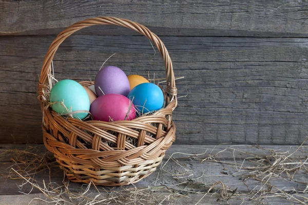 Huevos de Pascua en la cesta sobre tablas de madera — Foto de Stock