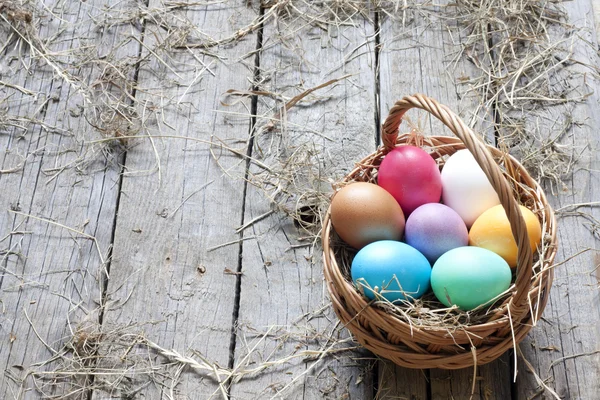 Huevos de Pascua en cesta sobre tablones de madera vintage fondo —  Fotos de Stock