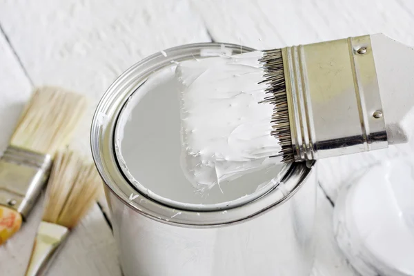 Paint brush and can on white planks — Stock Photo, Image