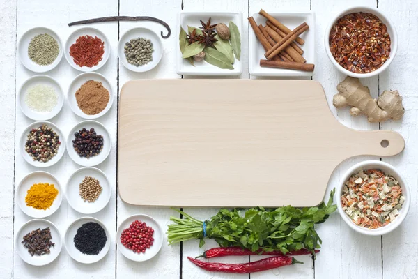 Spices and dried vegetables with cutting board on white planks — Stock Photo, Image
