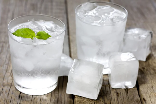 Glas Wasser mit Eiswürfeln auf alten Holzplanken — Stockfoto