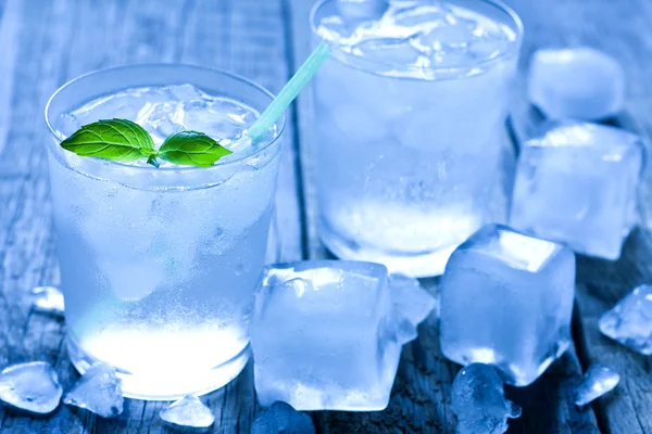 Glas vatten med isbitar på vintage plankor — Stockfoto