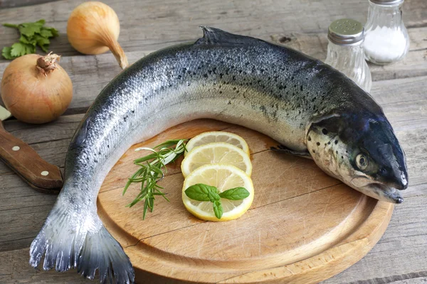 Pesce crudo di salmone sul tagliere in cucina con spezie — Foto Stock