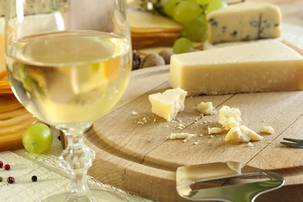 Queso y copa de vino de primer plano en la tabla de cortar — Foto de Stock