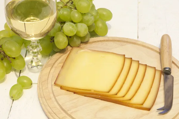 Queso y copa de vino de primer plano en la tabla de cortar — Foto de Stock