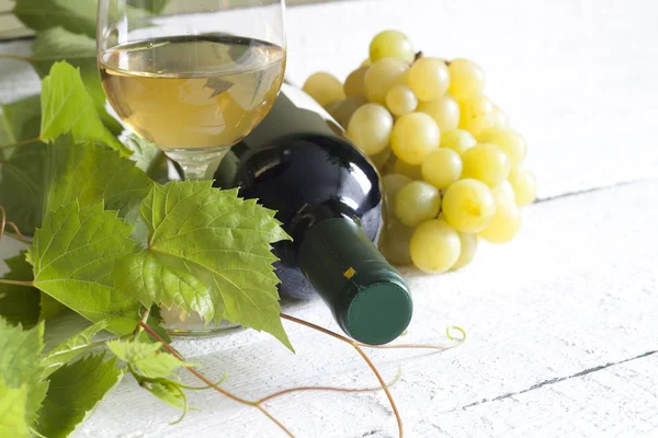 Glass of white wine with bottle and grapes on vintage boards — Stock Photo, Image