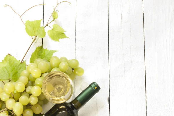 杯白葡萄酒与瓶和老式主板上葡萄 — ストック写真