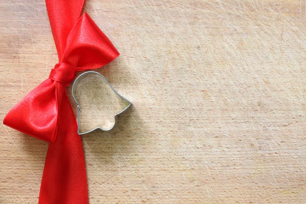 Red ribbon and bow on vintage cutting board christmas background — Stock Photo, Image