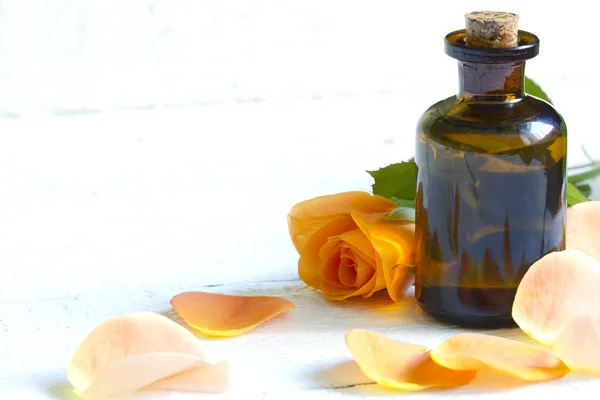 Rosa de aceite con pétalos sobre fondo blanco de madera — Foto de Stock