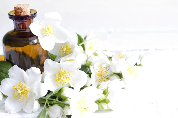 Aceite de aromaterapia de jazmín sobre tablones blancos con flores — Foto de Stock