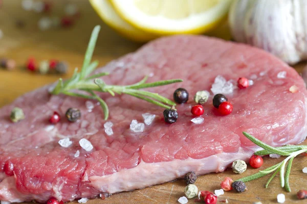Raw beef steak on cutting board with spices — Stock Photo, Image