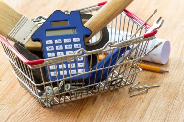 Alışveriş sepetindeki DIY araçları ve hesap makinesi, ev yapımı ve yenileme maliyetleri kavramı