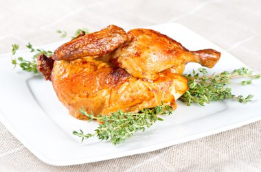 Beyaz bir tabakta otlu ızgara tavuk.