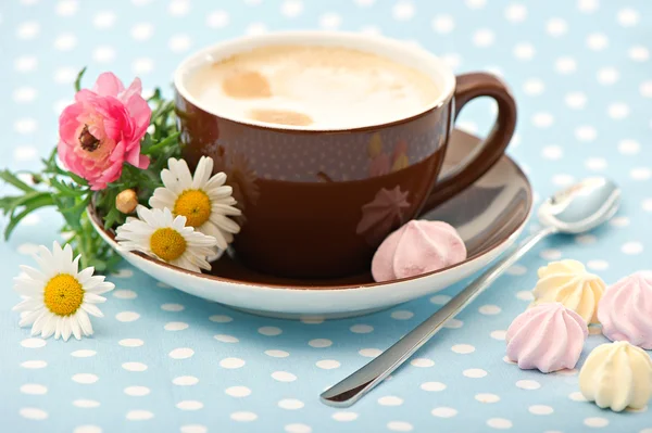 Чашка молочного кофе с цветами и сладостями — стоковое фото