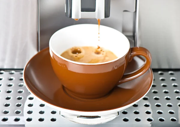 Coffee maker pouring fresh coffee in a cup