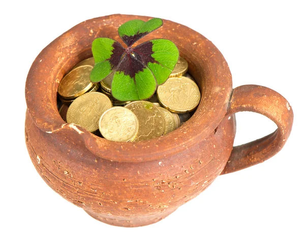 Old ceramic pot with money coins and clover leaf on white background — Stock Photo, Image