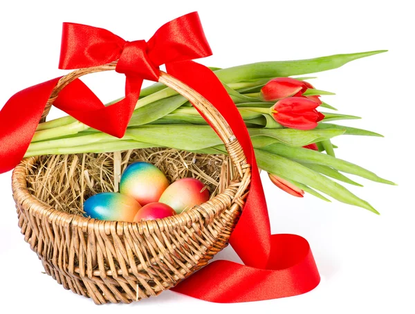 Colorful easter eggs in brown basket with red ribbon — Stock Photo, Image