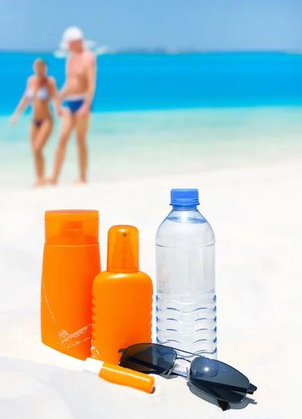 Proteção solar creme, água e óculos de sol — Fotografia de Stock