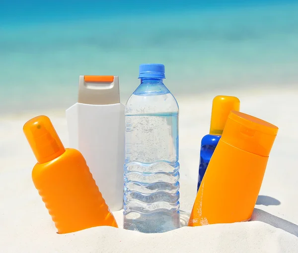 Water and sun protection cream on beach background — Stock Photo, Image