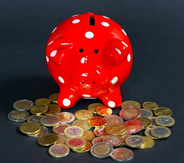 Евро монеты с красной сберегающей свиньей на черном фоне — стоковое фото