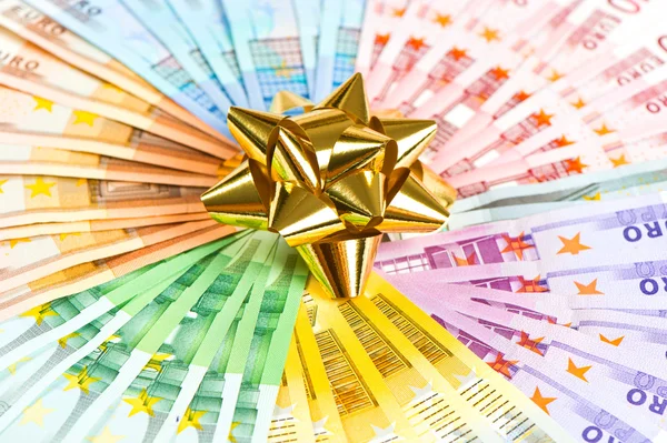 Peníze jako dárek. Zlatá stuha na pozadí bankovky eura — Stock fotografie