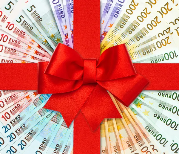 Lazo rojo de regalo sobre billetes en euros —  Fotos de Stock