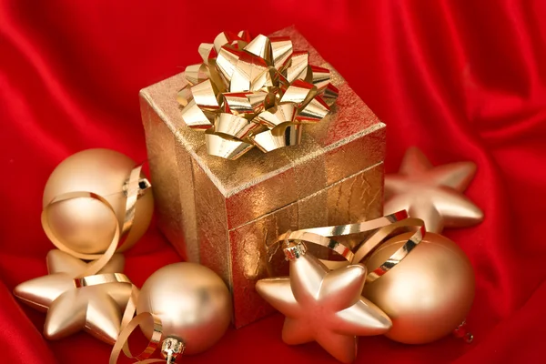 Gift box with golden christmas balls on red silk — Stock Photo, Image