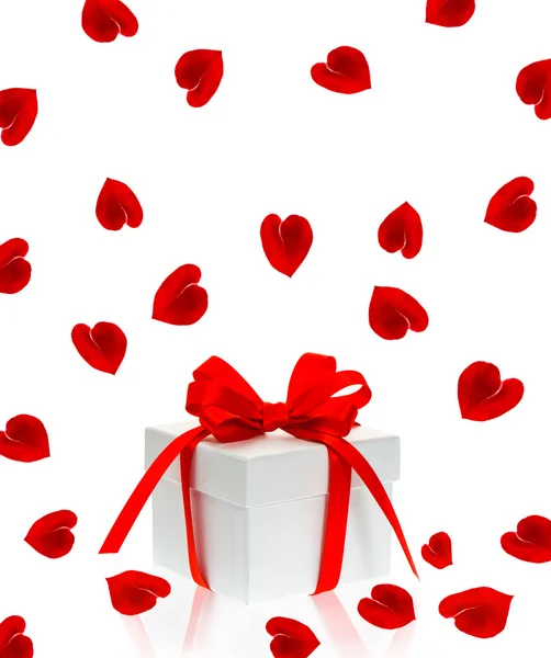 Συσκευασία δώρου με κόκκινη κορδέλα τόξο και το ροδαλό λουλούδι πέταλα — Φωτογραφία Αρχείου