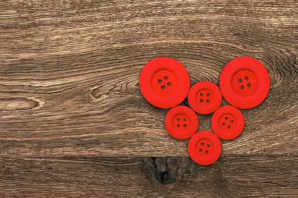 Botões vermelhos em forma de coração sobre fundo de madeira — Fotografia de Stock