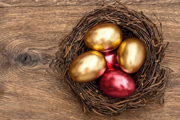 Ovos de páscoa dourados e vermelhos no ninho — Fotografia de Stock