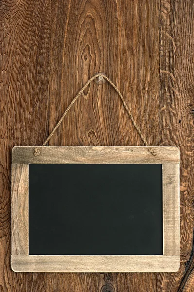 Blackboard vintage pendurado na parede de madeira — Fotografia de Stock