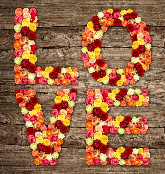 LOVE, roses flower letters over wooden background — Stock Photo, Image