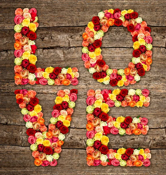 AMOR, rosas letras de flores sobre fundo de madeira — Fotografia de Stock