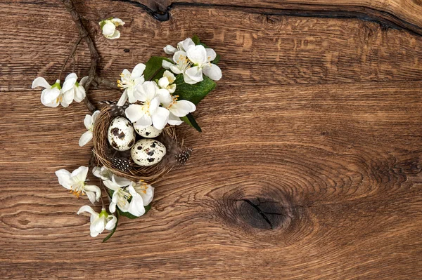 Fleurs et nid de Pâques avec des œufs sur fond en bois — Photo