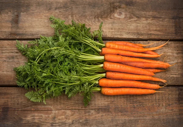 Bunch of fresh carrots over wooden background — Stock Photo, Image