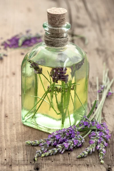 Botella de aceite de lavanda con flores frescas —  Fotos de Stock