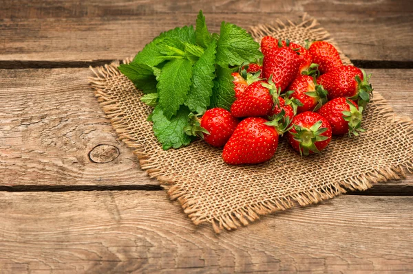 Fraises fraîches avec feuilles de menthe sur fond bois — Photo