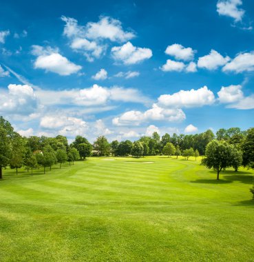 Yeşil golf alanı ve bulutlu gökyüzü mavi