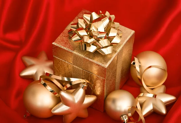 Gift box with golden christmas balls on red silk — Stock Photo, Image