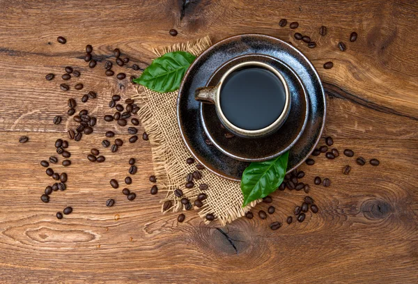 Чашка черного кофе с бобами на деревянном фоне — стоковое фото