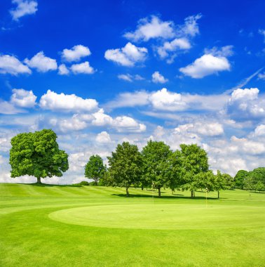 Yeşil golf sahası ve bulutlu gökyüzü mavi