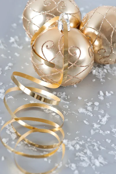 Goldene Weihnachtskugeln mit goldenen Luftschlangen und Schnee — Stockfoto