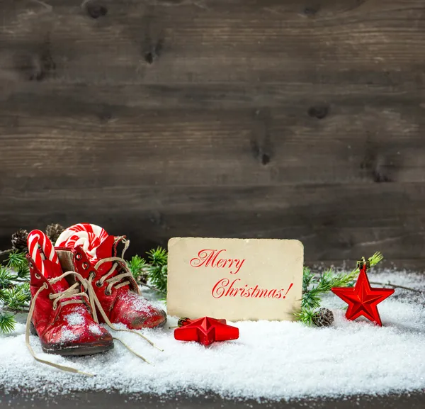 Decorazioni natalizie stelle rosse e scarpe da bambino antiche sulla neve — Foto Stock