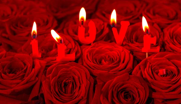 Rosas rojas y velas encendidas haciendo AMO — Foto de Stock