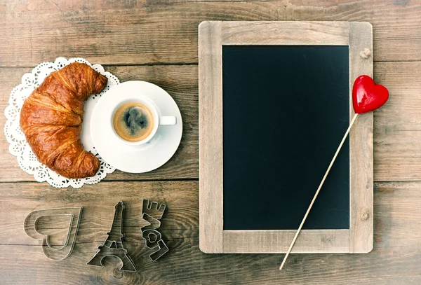 Кофе с круассаном, доска и украшения сердца — стоковое фото
