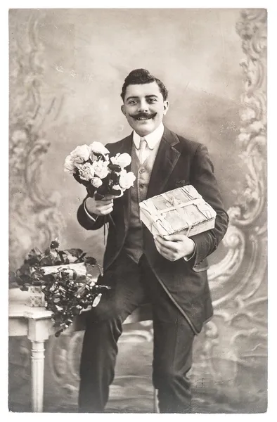 Portrait of young man with rose flowers and gift — Stock Photo, Image