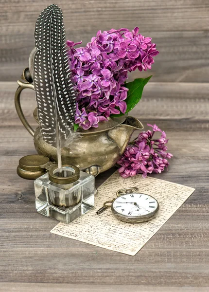 Lilac flowers and antique inkwell on wooden background — Stock Photo, Image